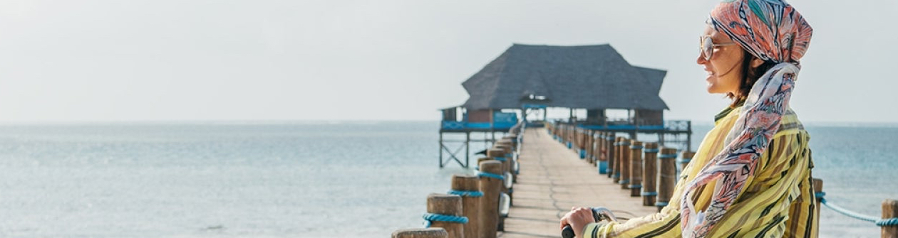 Une femme sur son vélo sur un ponton allant à la mer